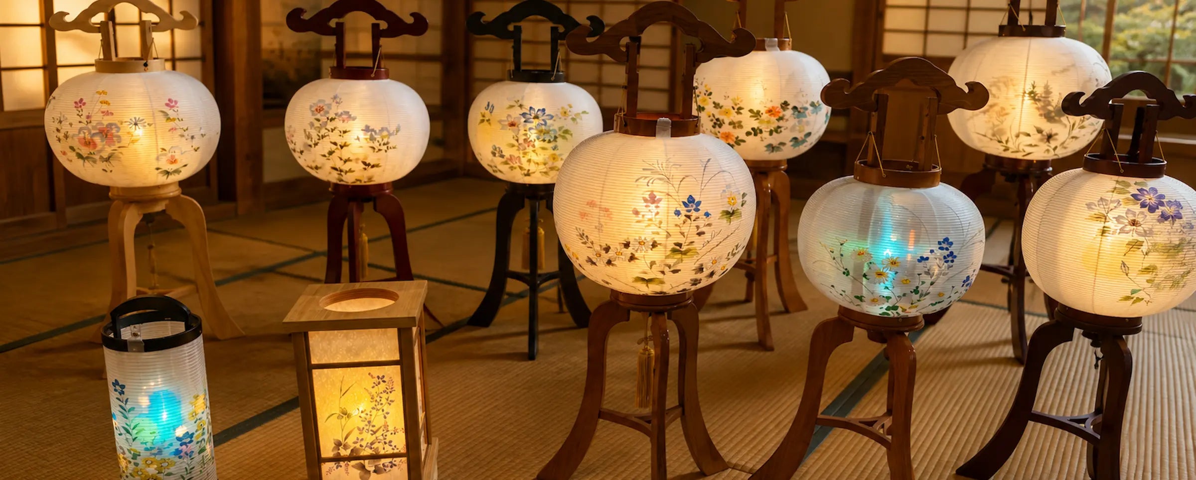 Collection of vintage Japanese Bon Odori paper lanterns with hand-painted floral designs displayed in a traditional Japanese room