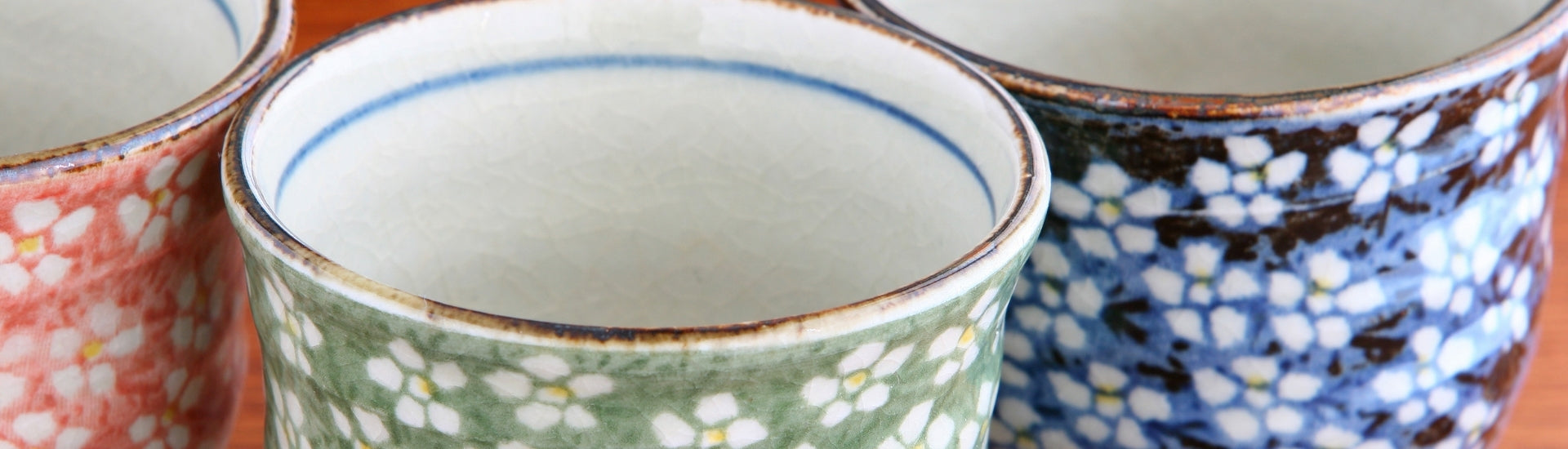 Japanese teacups (yunomi) with floral ceramic patterns in green, blue, and red glaze detail
