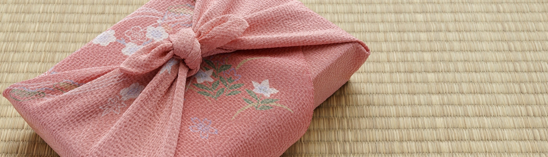 Japanese furoshiki wrapping cloth tied in a traditional knot around a package, showing fabric texture and floral pattern