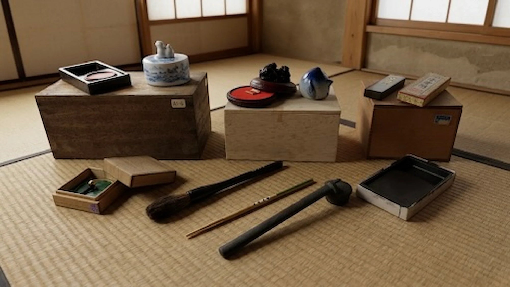 Collection of vintage Japanese calligraphy tools including brushes, inkstones, ink sticks, and writing accessories displayed in a traditional Japanese room setting