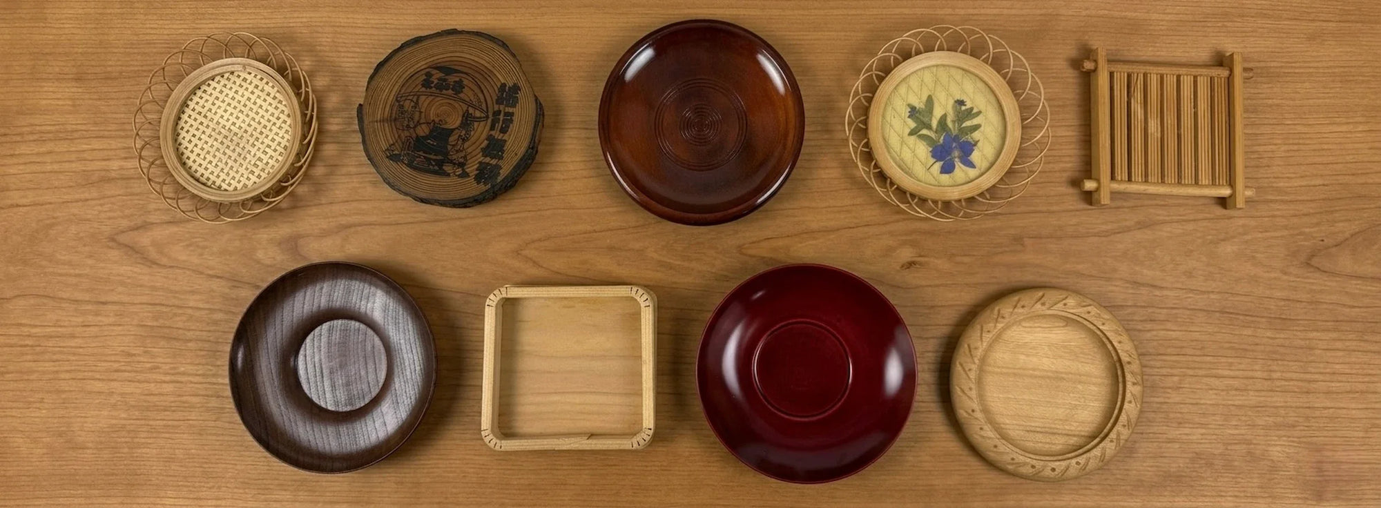 Vintage Japanese coasters made from wood, bamboo, and lacquerware displayed on a natural wood tabletop.