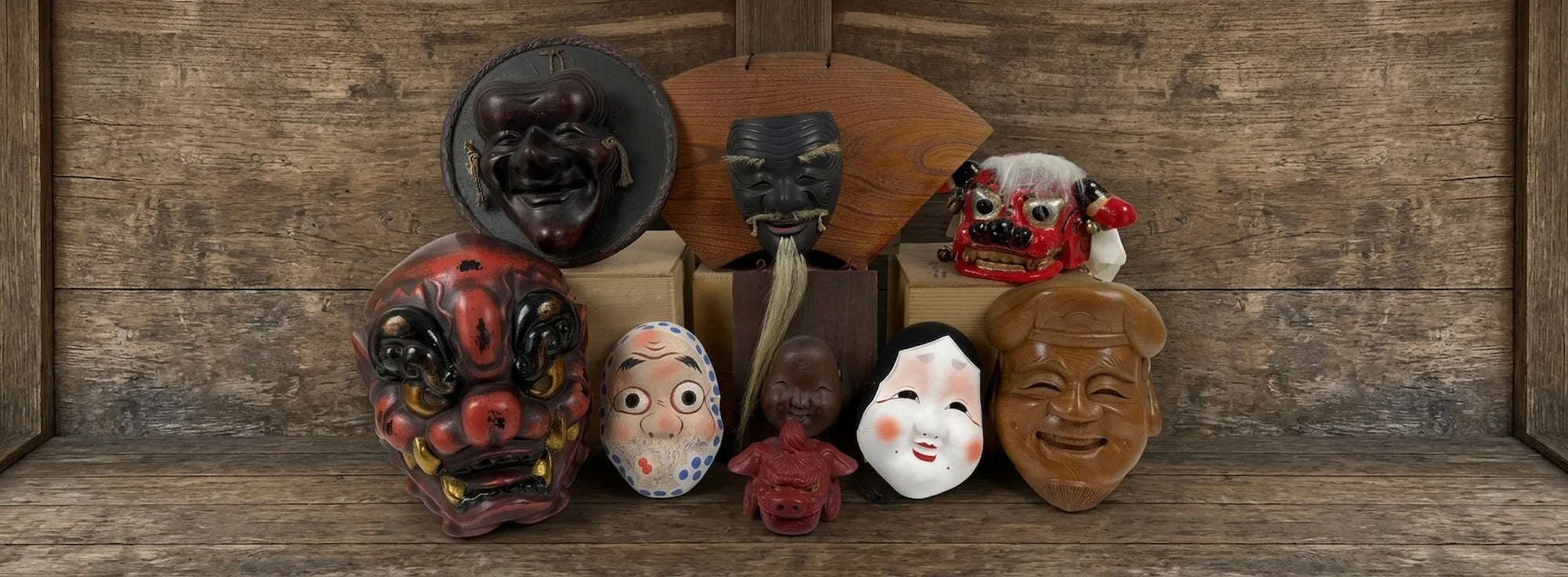 Vintage Japanese masks including Tengu, Okame, Otafuku, festival masks, and folk art masks displayed against a traditional wooden backdrop.