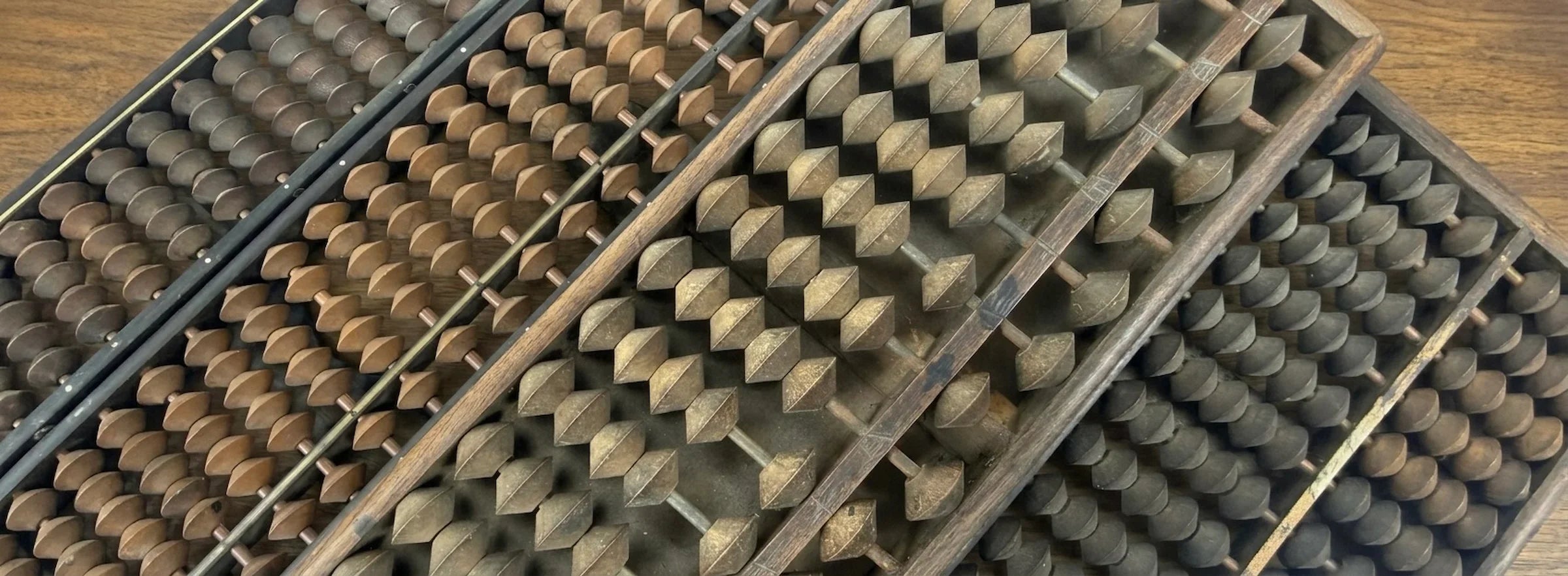 Vintage Japanese soroban abacuses arranged diagonally on a wooden tabletop, highlighting traditional calculation tools and craftsmanship.