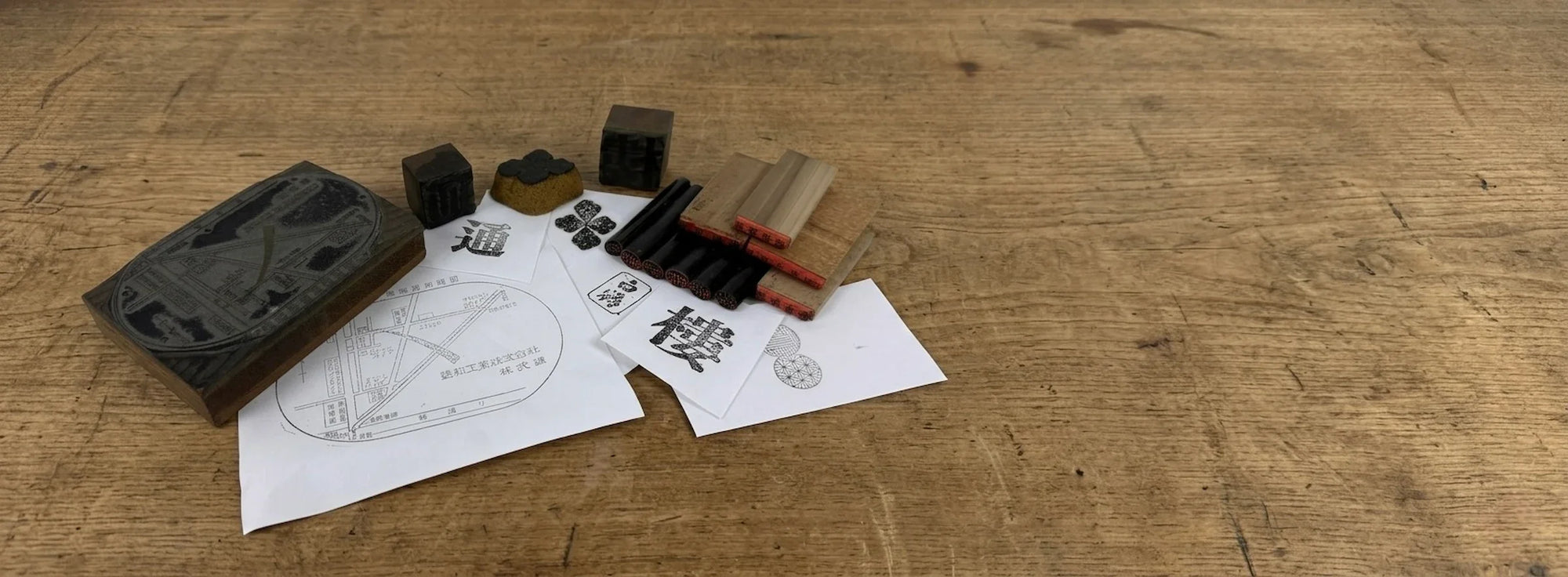 Vintage Japanese stamps, hanko seals, inkan, and woodblock printing tools displayed on a traditional wooden workbench.